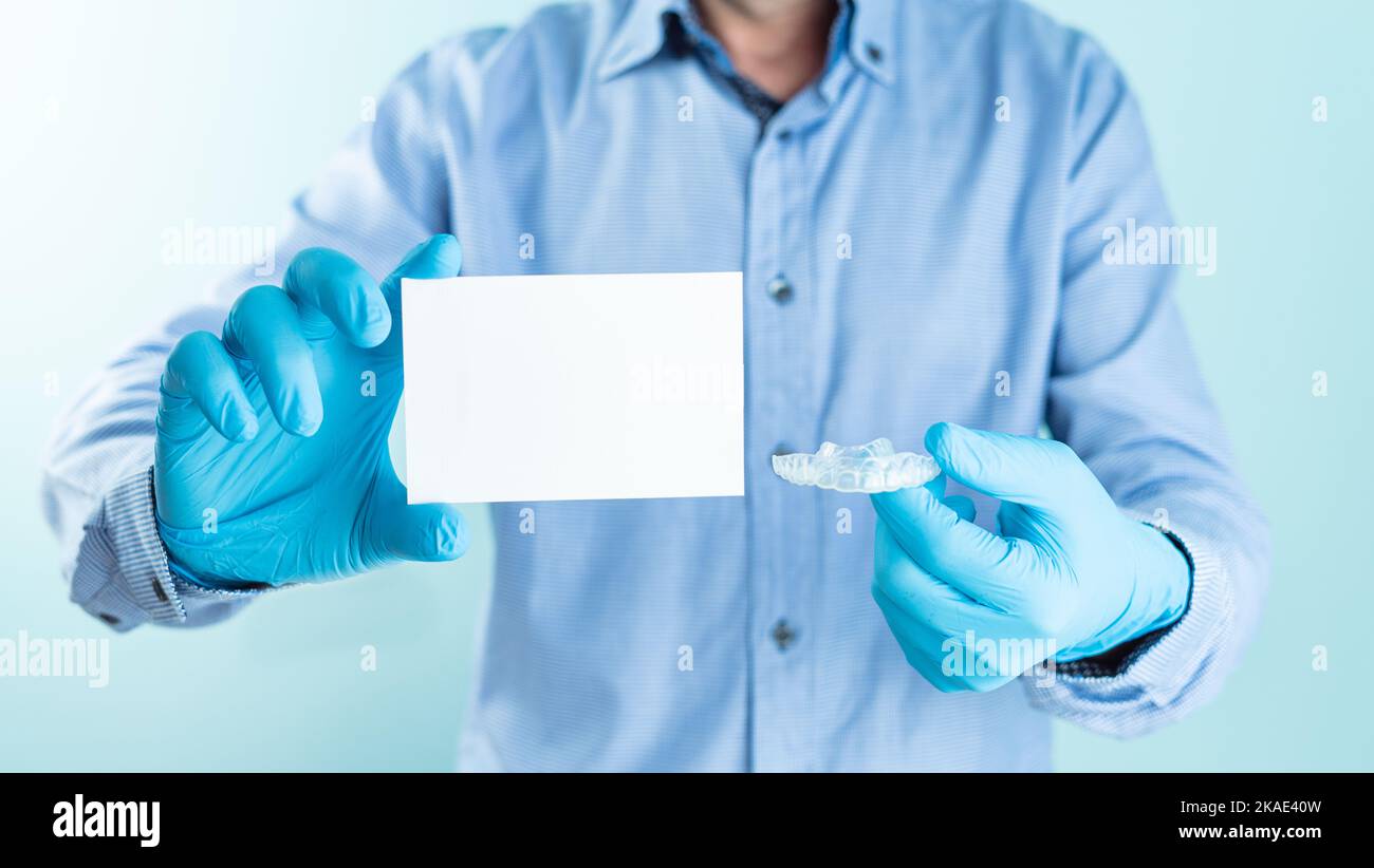 Medico che mostra ortodonzia invisibile da una parte e carta bianca per il testo dall'altra parte. Scheda mockup per il testo. Foto Stock
