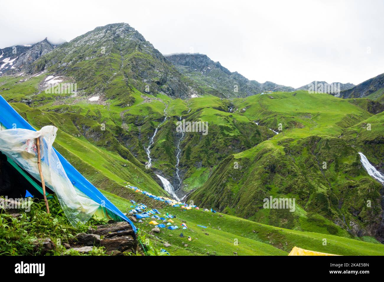 Luglio 14th 2022, Himachal Pradesh India. Numerose tende colorate al campo base di Bheem Dwari con splendide vette e cascate nel backgrou Foto Stock