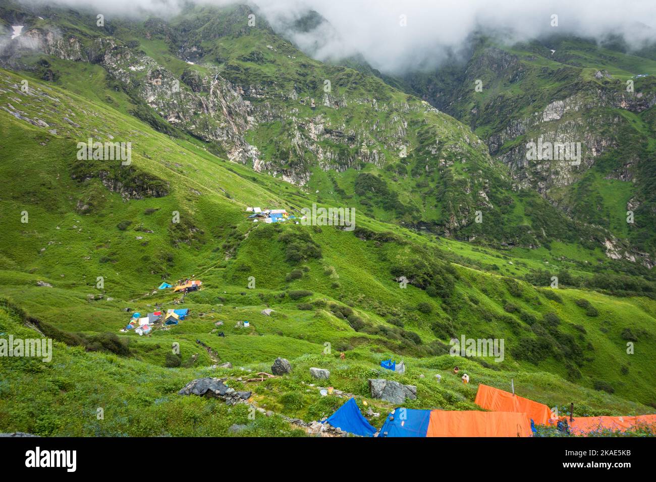 Luglio 14th 2022, Himachal Pradesh India. Numerose tende colorate al campo base di Bheem Dwari con splendide vette e cascate nel backgrou Foto Stock