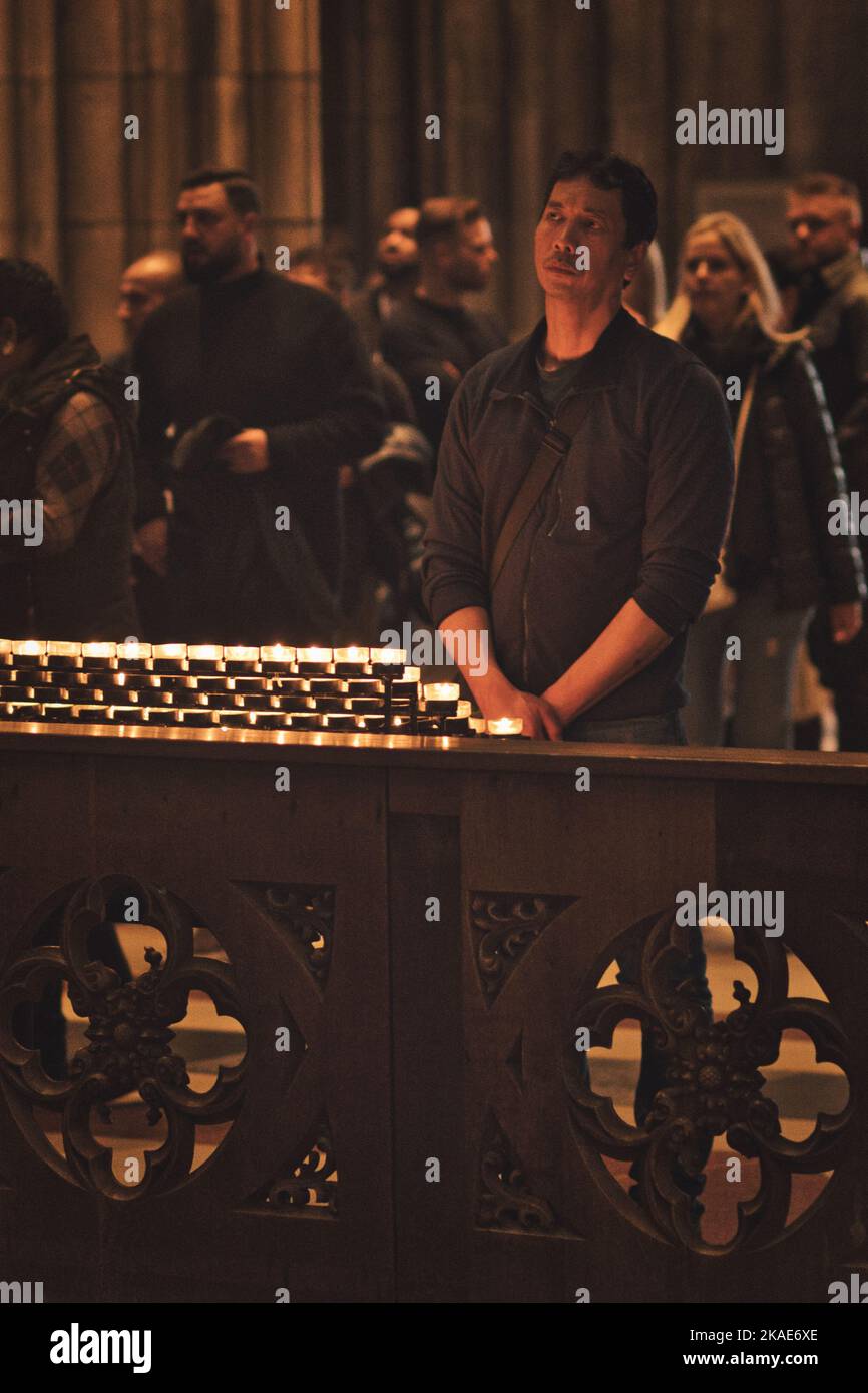 Un colpo verticale di persone che tengono devozioni di fronte a un mare di candele nella Cattedrale di Colonia, in Germania Foto Stock