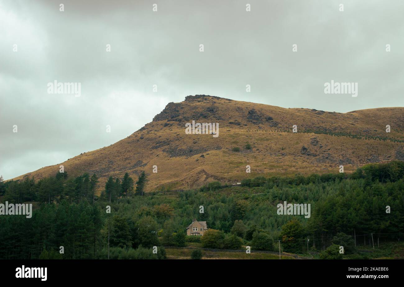 Una collina che torreggia su una singola casa in Inghilterra. Foto Stock