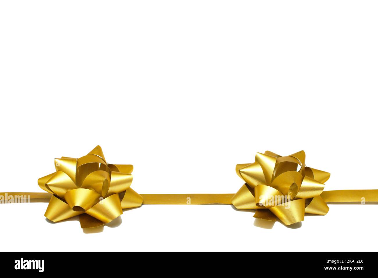 Due archi regalo dorati con un nastro su sfondo bianco con spazio copia. Oggetto isolato. Modello universale per cartoline, poster, banner. Foto Stock