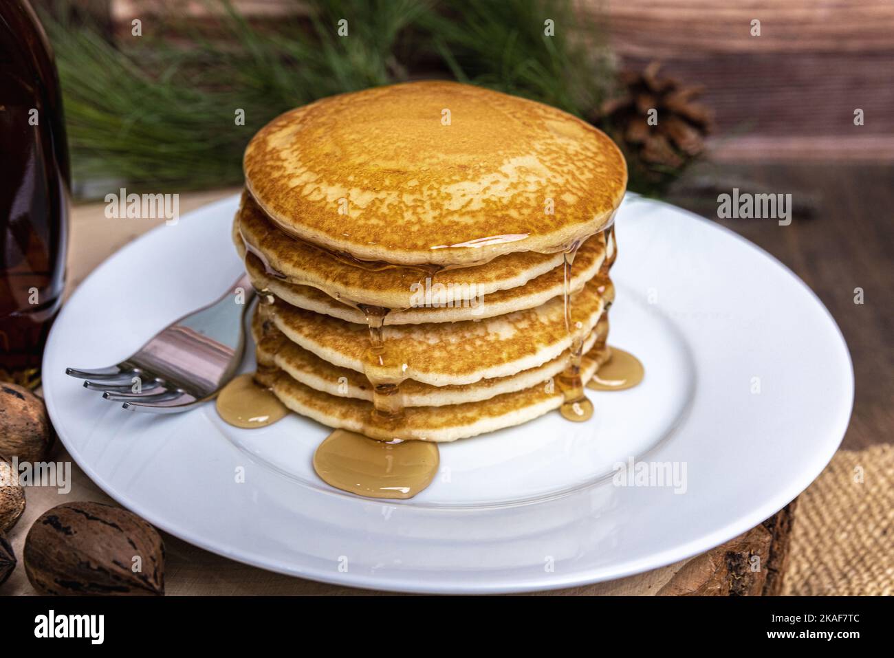 Un piatto grande di frittelle con una forchetta e sciroppo versato sopra Foto Stock