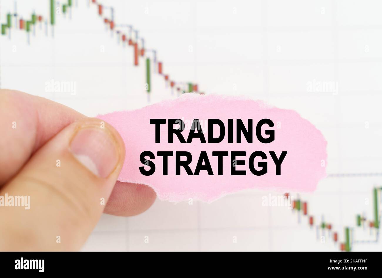 Concetto commerciale e commerciale. Sullo sfondo del grafico di citazione, un uomo tiene un segno con l'iscrizione - strategia commerciale Foto Stock