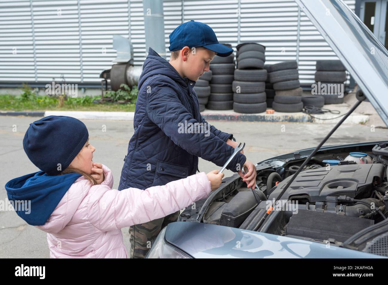 I bambini riparano l'auto all'aperto. Concetto di riparazione automatica Foto Stock