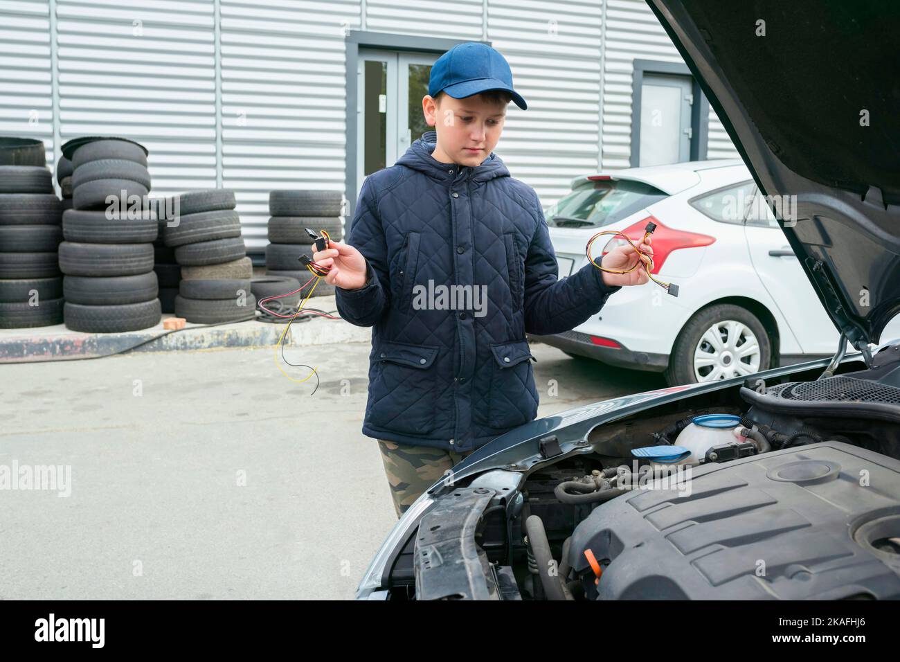 Un meccanico bambino cambia i fusibili in un'auto. Servizi di riparazione nel servizio auto. Concetto di riparazione automatica Foto Stock