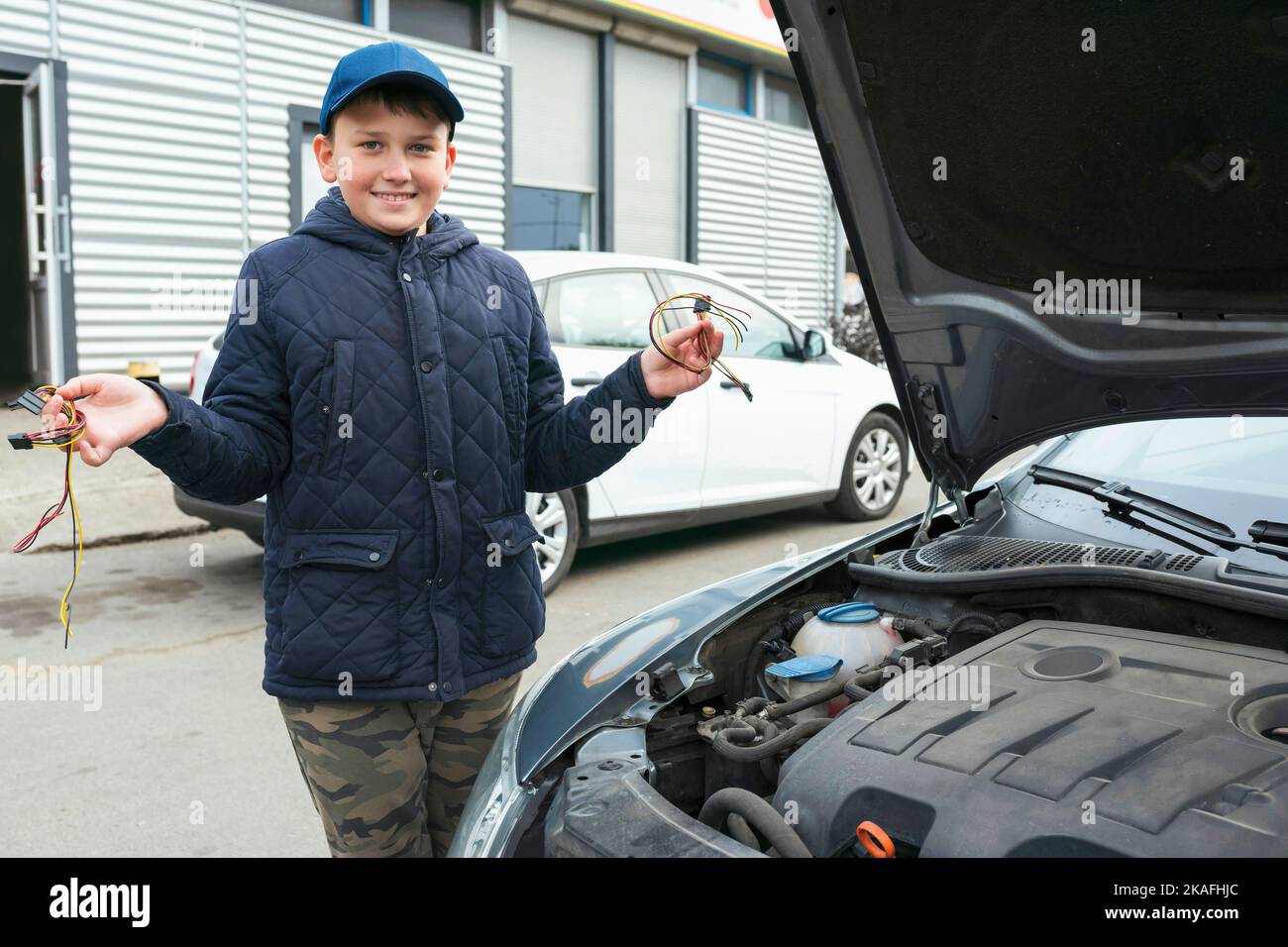 Un bambino meccanico lavora in un garage, all'aperto. Servizi di riparazione auto. Servizio auto Foto Stock
