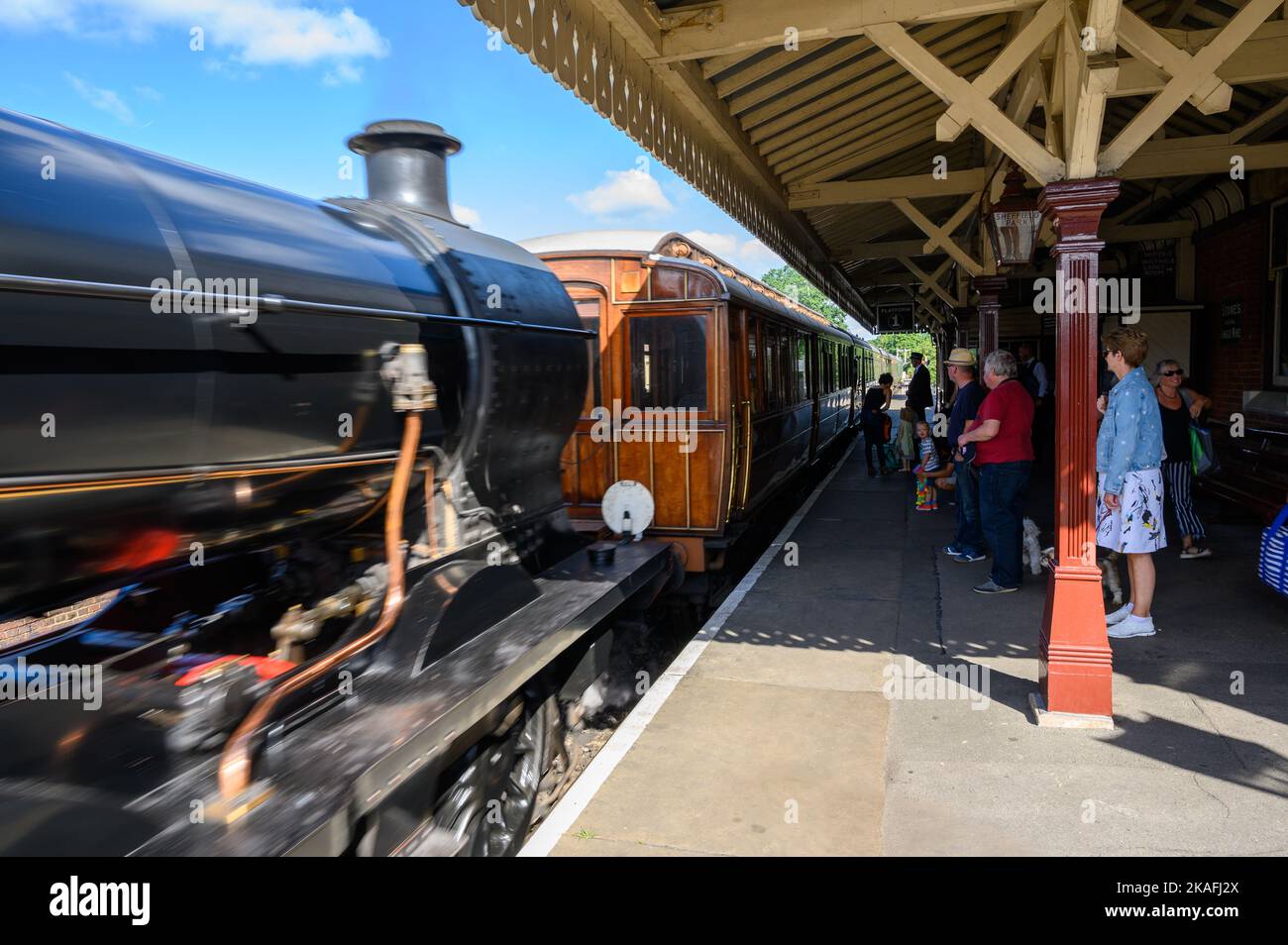 Un treno a vapore vintage che arriva con i passeggeri in attesa sulla piattaforma 1 alla stazione di Sheffield Park sulla linea ferroviaria Bluebell, East Sussex, Inghilterra. Foto Stock