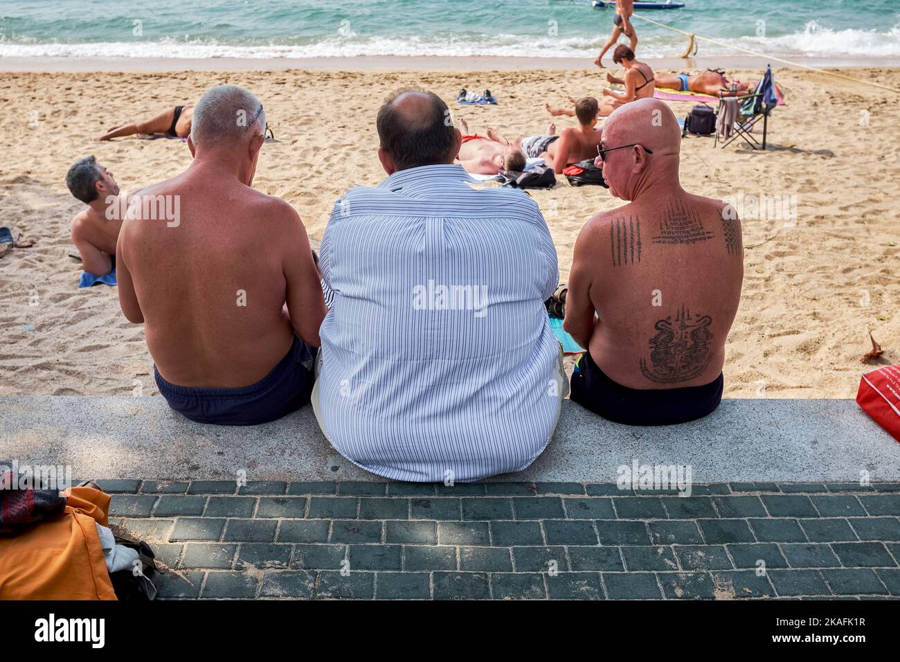 Un turista occidentale in sovrappeso seduto sulla spiaggia di Pattaya, Thailandia Foto Stock