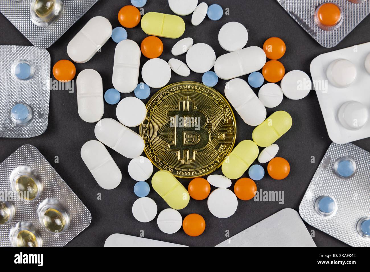 Pagamento di fatture mediche con bitcoin o criptovaluta concetto foto. Un bitcoin tra le pillole o le droghe su sfondo nero. Foto Stock