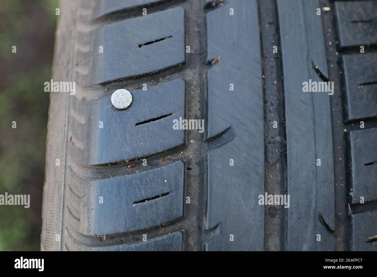 Un chiodo in un pneumatico di automobile. La ruota è danneggiata. Ciò può causare una foratura. Foto Stock