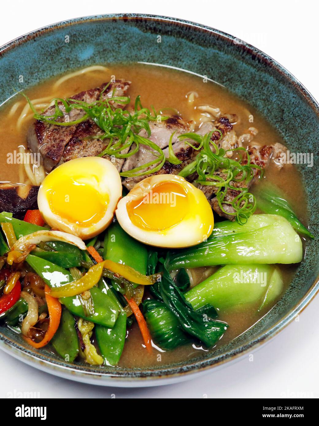 zuppa di spaghetti ramen con strisce di manzo, uova in camicia, bok choi e verdure estive in una ciotola Foto Stock