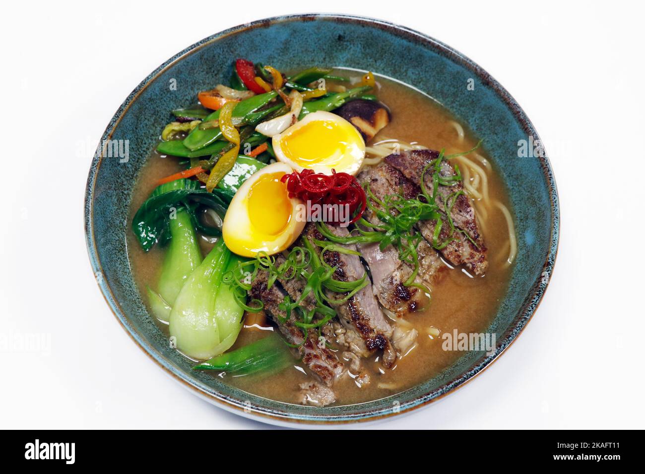 zuppa di spaghetti ramen con strisce di manzo, uova in camicia, bok choi e verdure estive in una ciotola Foto Stock