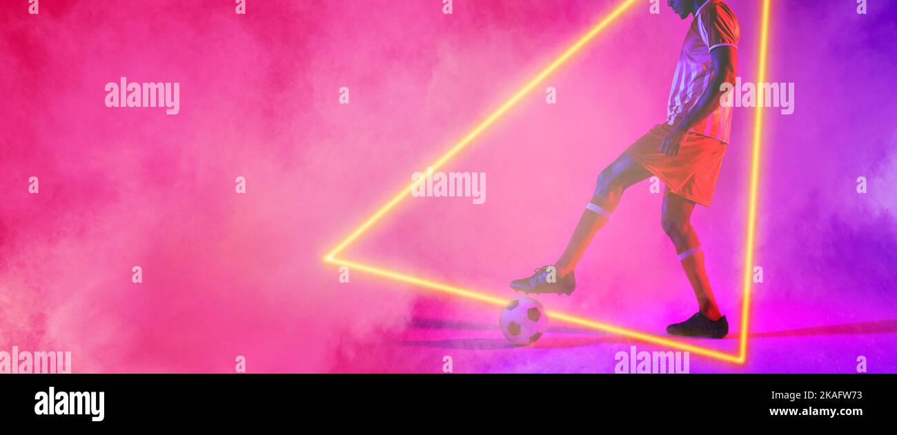 Sezione bassa del giocatore maschio che pratica con la sfera sopra la forma del triangolo illuminato contro fumo Foto Stock