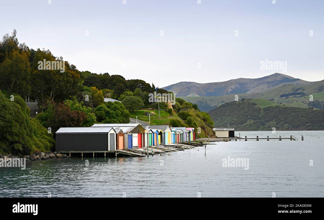 Capannoni multicolore sulla riva di Robinsons Bay, Akaroa, Nuova Zelanda Foto Stock
