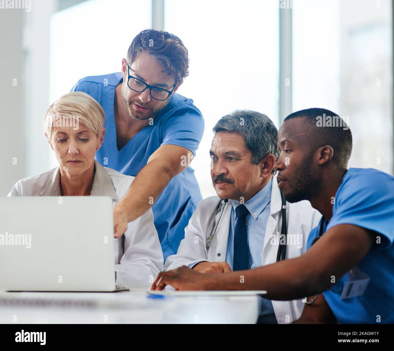 Risoluzione dei problemi medici, come i professionisti lo fanno. Un team di medici che utilizzano un computer portatile insieme durante una riunione. Foto Stock