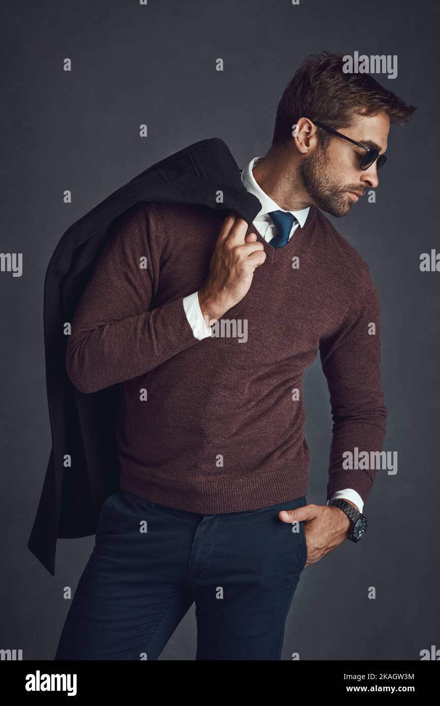 Il maschio alfa di stile. Studio di un giovane vestito con stile che porta la giacca su uno sfondo grigio. Foto Stock