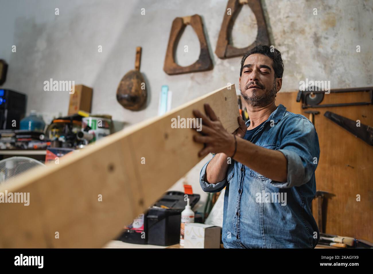 Un falegname controlla visivamente una tavola di legno nel suo negozio d'epoca - concetto di lavorazione del legno, piccole imprese, antichi mestieri e piccoli artigiani Foto Stock