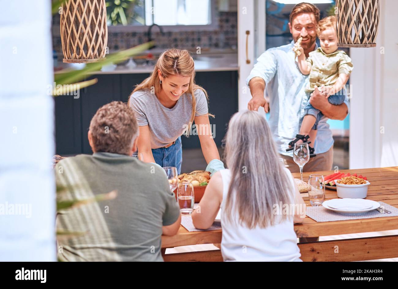 Pollo, pranzo e grande famiglia mangiare in un tavolo da pranzo nella loro casa con amore, sorriso e festa insieme. Cibo, felice e donna con un Foto Stock