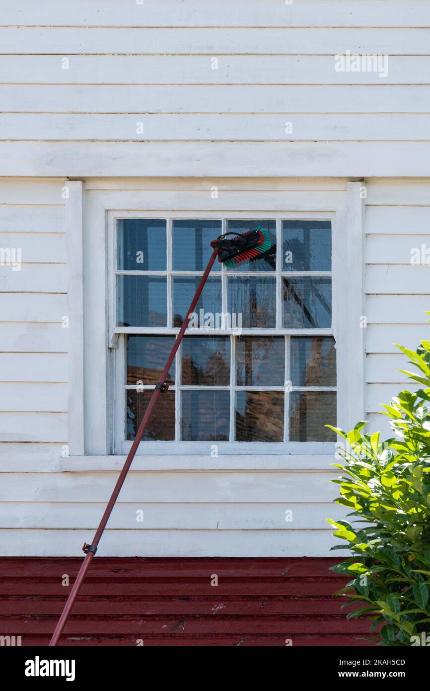 Pulizia della finestra al piano superiore con sistema di pali alimentati ad acqua - Inghilterra, Regno Unito Foto Stock