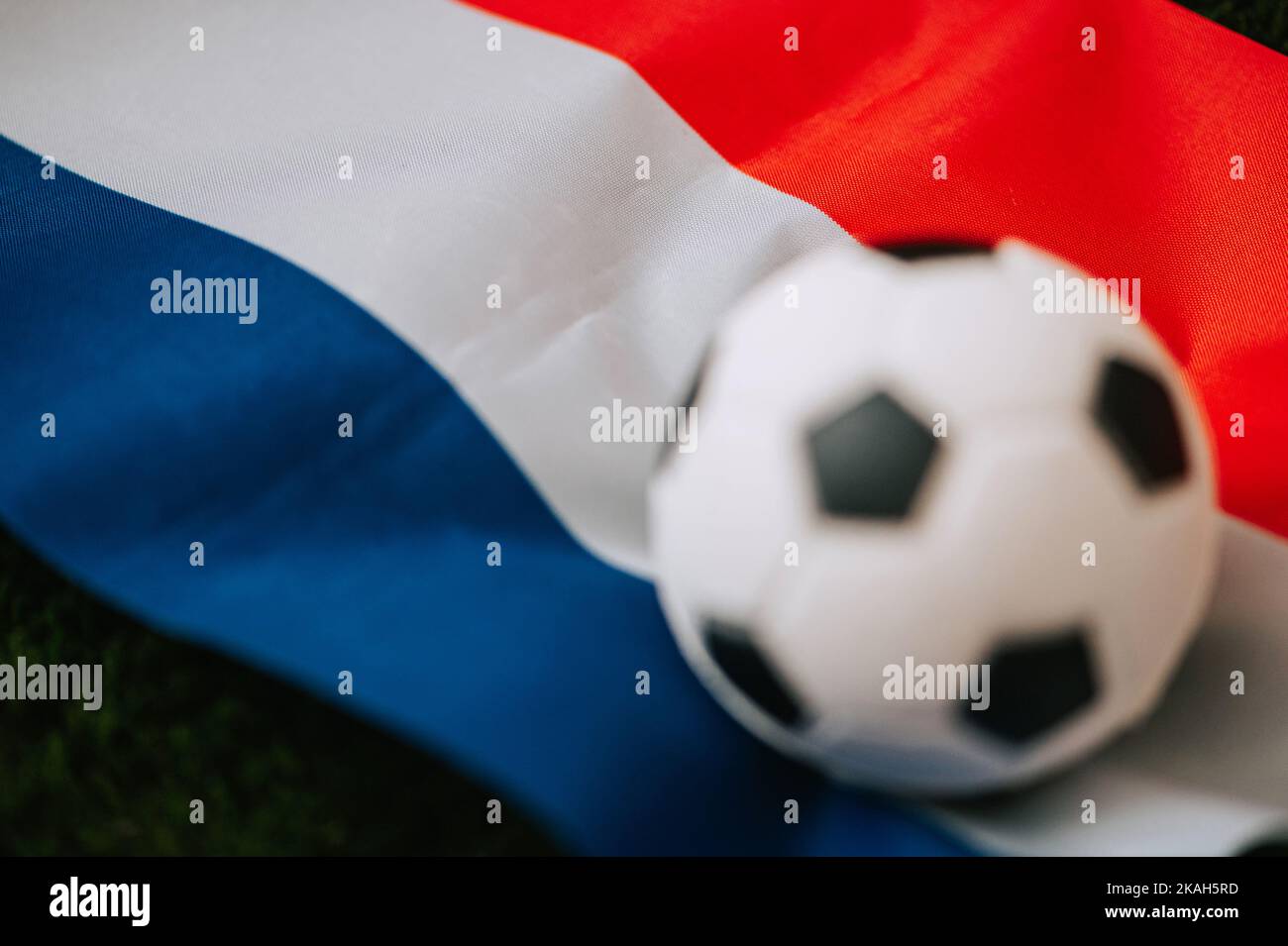 Nazionale di calcio olandese. Bandiera nazionale su erba verde e palla da calcio. Carta da parati da calcio per Campionato e Torneo nel 2022. Il mondo in Foto Stock