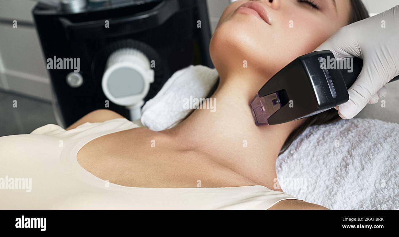 Primo piano procedura di sollevamento del collo RF per la giovane donna per stringere e migliorare le condizioni della sua pelle. Sollevamento RF Foto Stock
