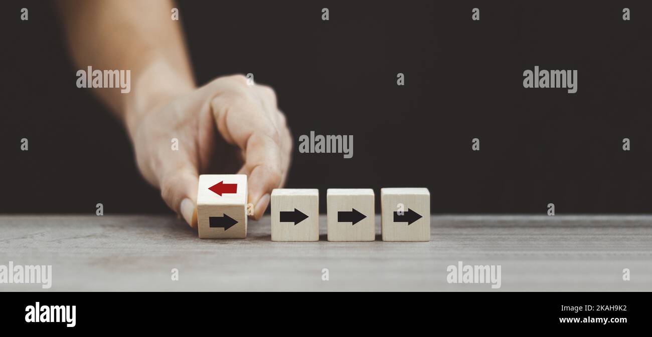 Mano che capovolgono il blocco di legno del cubo freccia da sinistra a destra per la rottura di affari e l'idea differente di pensiero. Foto Stock