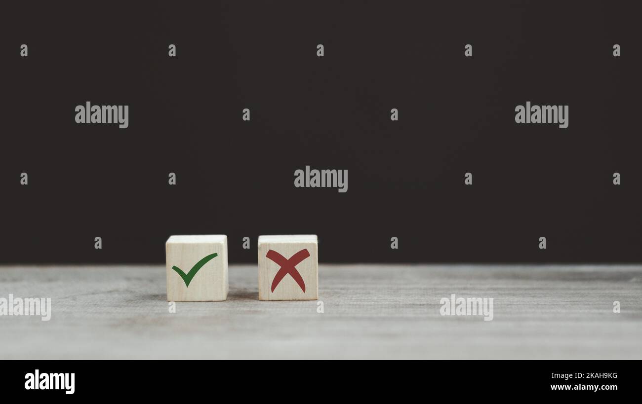Segno di spunta e segno di croce x su cubi di legno. Blocchi di legno con segno di spunta verde e rosso x. Concetto di presa di decisione positiva o negativa o di scelta o. Foto Stock