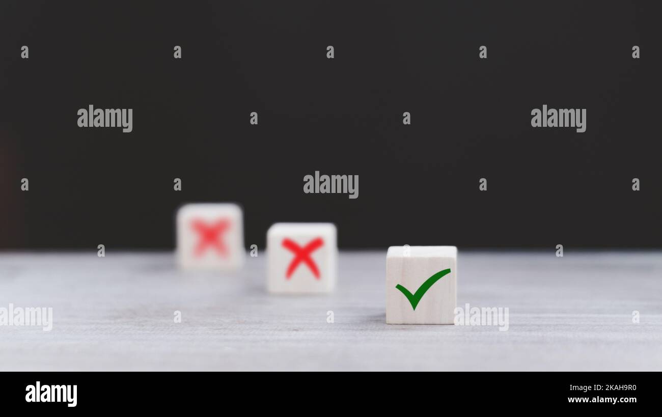 Segno di spunta e segno di croce x su cubi di legno. Blocchi di legno con segno di spunta verde e rosso x. Concetto di presa di decisione positiva o negativa o di scelta o. Foto Stock