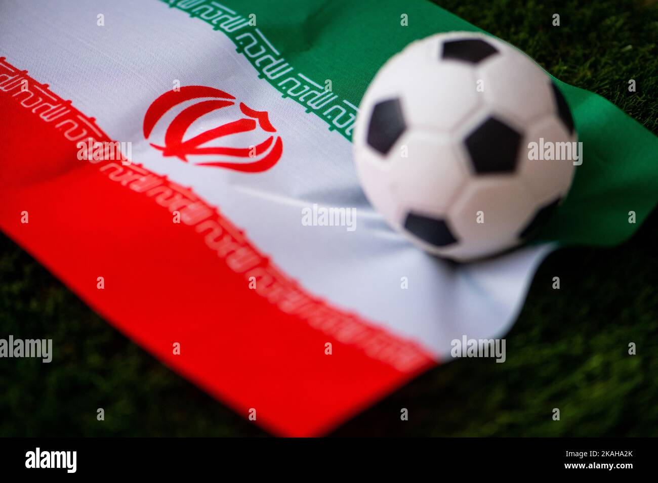 Nazionale di calcio dell'Iran. Bandiera nazionale su erba verde e palla da calcio. Carta da parati da calcio per Campionato e Torneo nel 2022. Internazionale Foto Stock