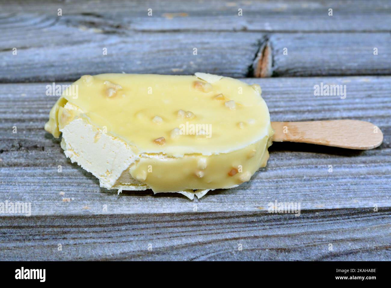 Bastone gelato alla vaniglia rivestito e ricoperto con uno strato di cioccolato bianco con noci, ricco gelato alla vaniglia in cracking cioccolato bianco e. Foto Stock