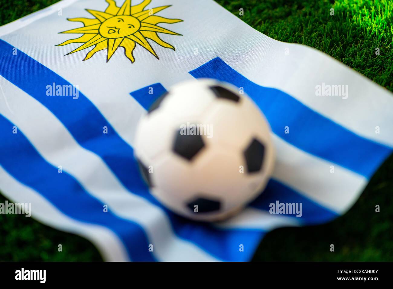 Nazionale di calcio dell'Uruguay. Bandiera nazionale su erba verde e palla da calcio. Carta da parati da calcio per Campionato e Torneo nel 2022. Intern. Mondo Foto Stock