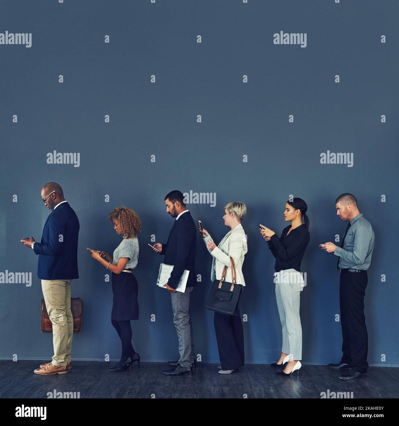 In linea per le opportunità. Studio di un gruppo di uomini d'affari che utilizzano dispositivi wireless mentre sono in attesa in linea. Foto Stock