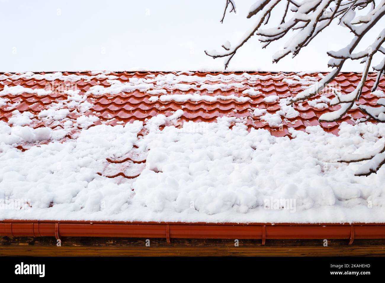 la neve scivola giù da un tetto di metallo-tegole dopo una nevicata pesante in inverno. Pericolo di caduta di neve dai tetti. Foto Stock