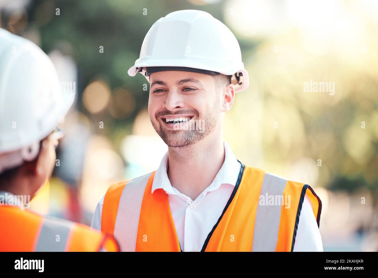 Sicurezza, architettura e felice ingegnere in un cantiere di costruzione parlando o parlando in una casa ristrutturazione. Smile, appaltatore e partner di progettazione Foto Stock