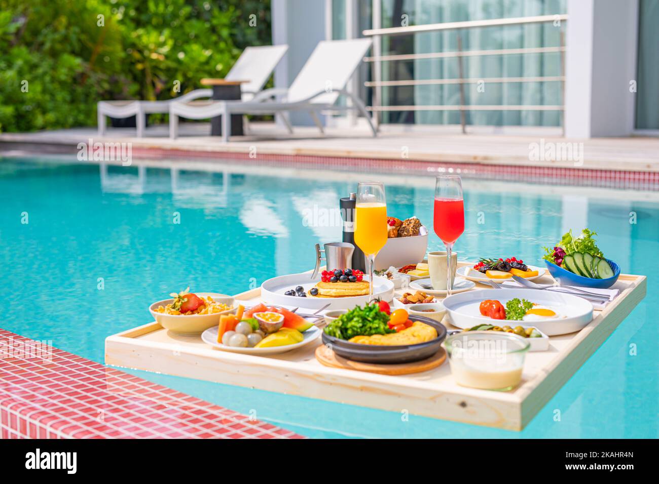 Colazione nella piscina del resort, colazione galleggiante nel lussuoso resort tropicale. Tavolo galleggiante sull'acqua tranquilla della piscina, colazione sana e piatto di frutta Foto Stock