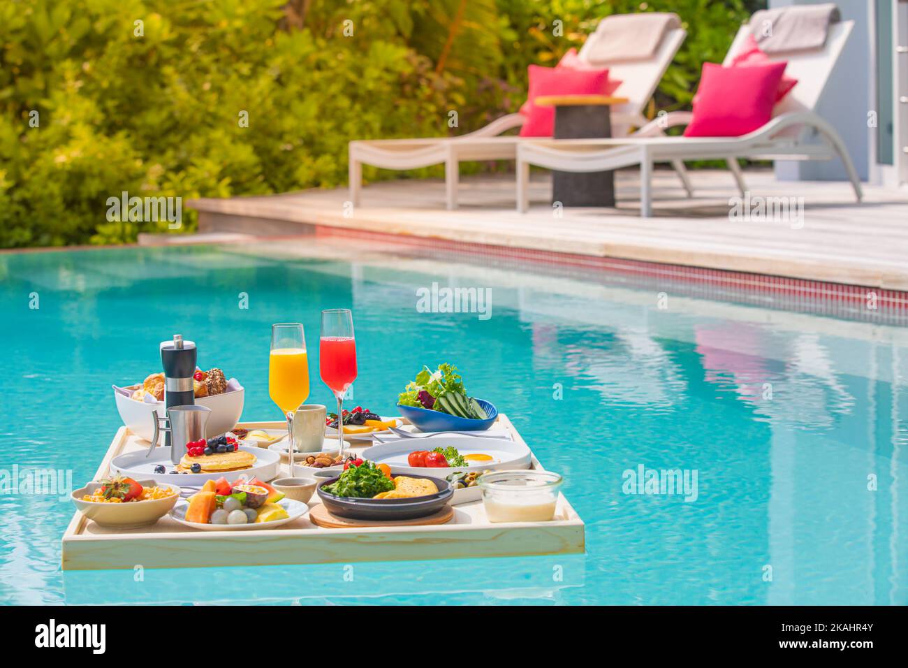 Colazione nella piscina del resort, colazione galleggiante nel lussuoso resort tropicale. Tavolo galleggiante sull'acqua tranquilla della piscina, colazione sana e piatto di frutta Foto Stock