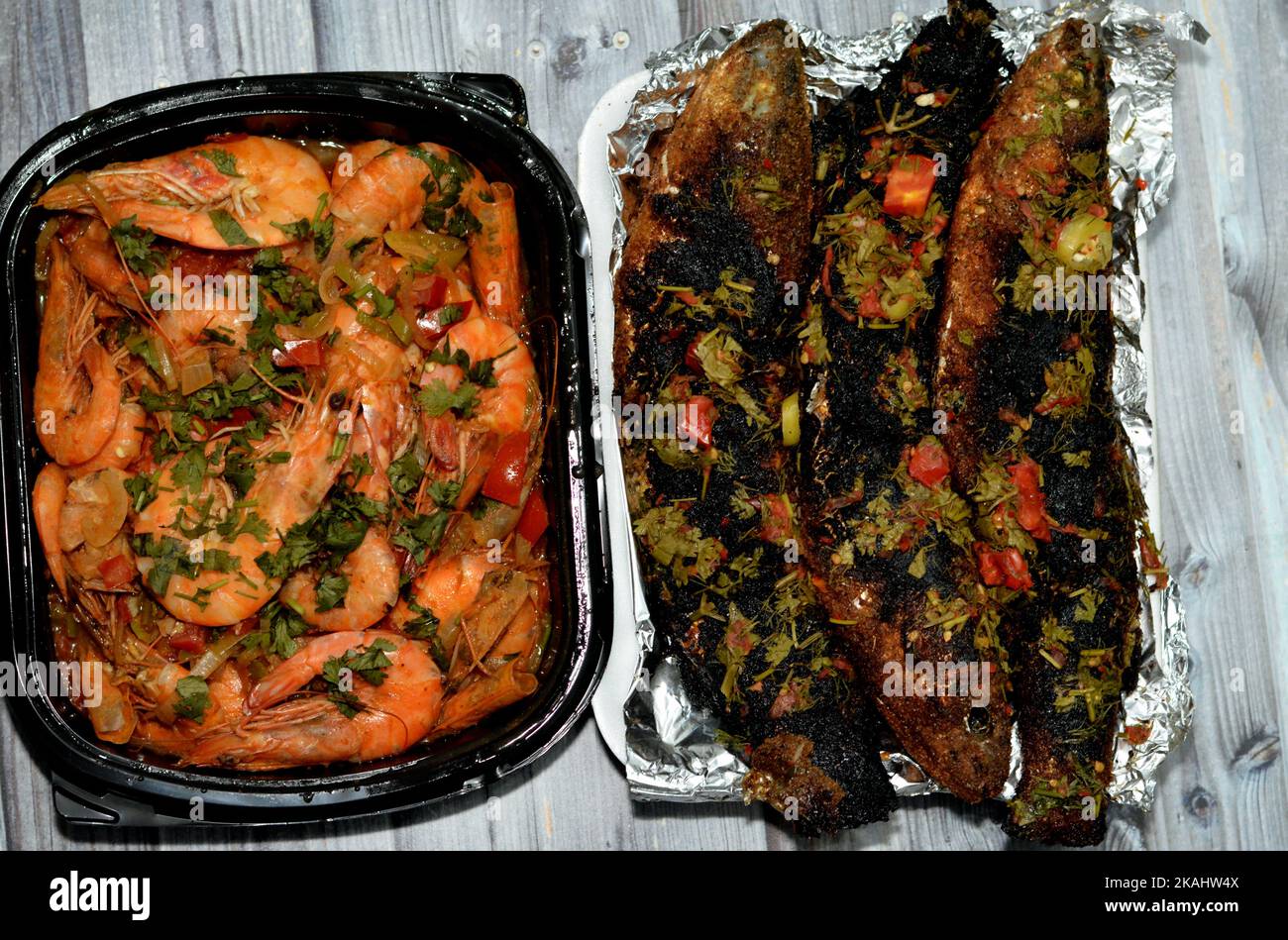 Cucina a base di pesce di gamberi bolliti, aglio, limone, prezzemolo, pepe, cipolla e pomodoro e triglie grigliate al carbone con prezzemolo e t Foto Stock