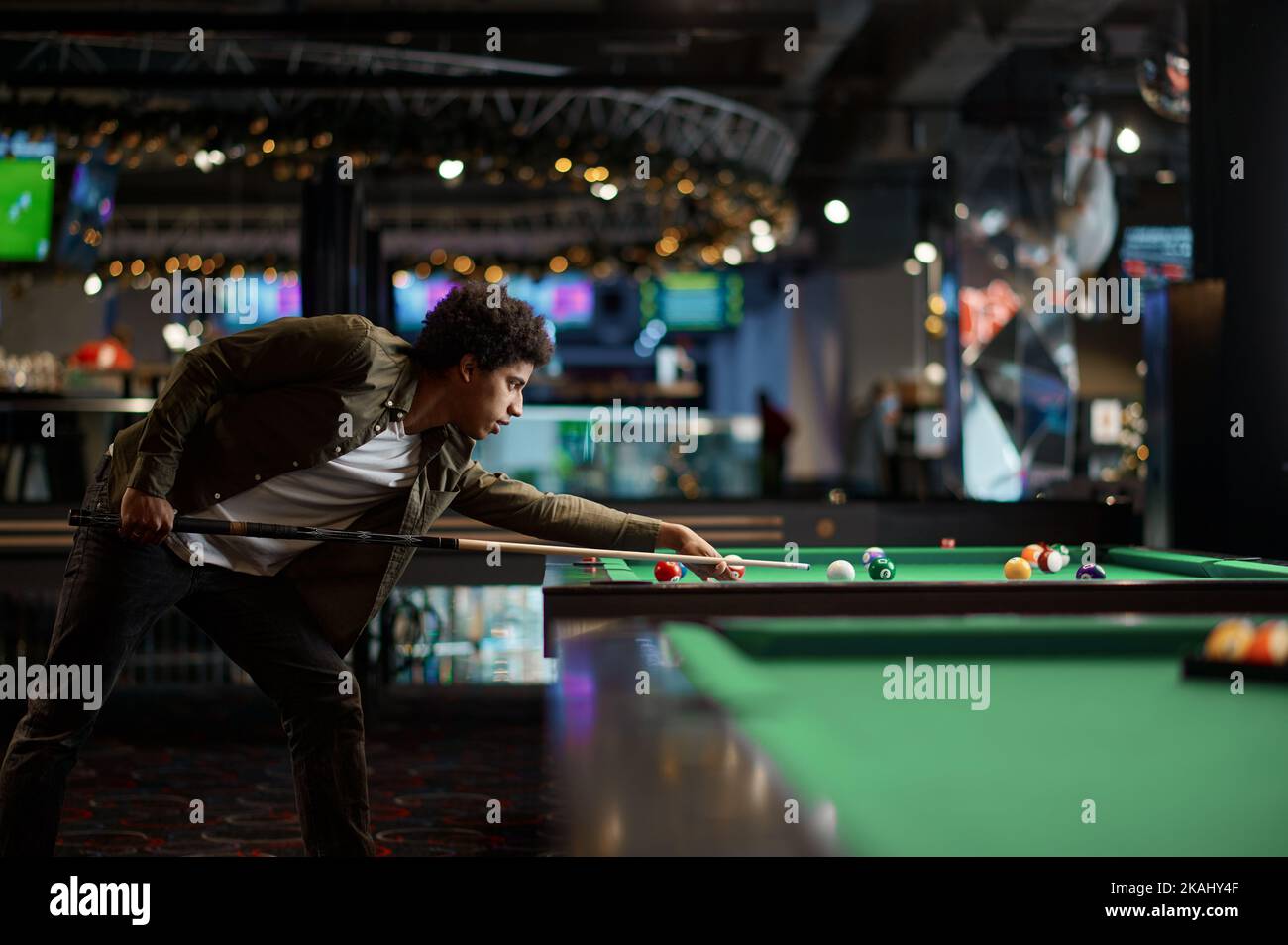 Ritratto di giovane uomo che prepara stecca da biliardo Foto Stock