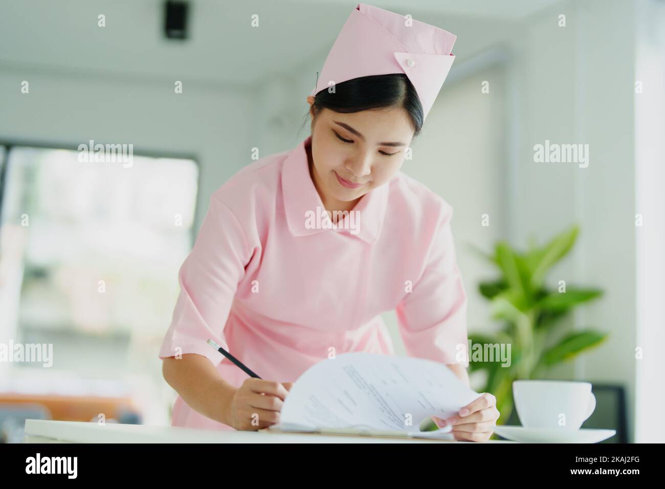 Ritratto di una giovane infermiera asiatica che guarda i documenti del paziente Foto Stock