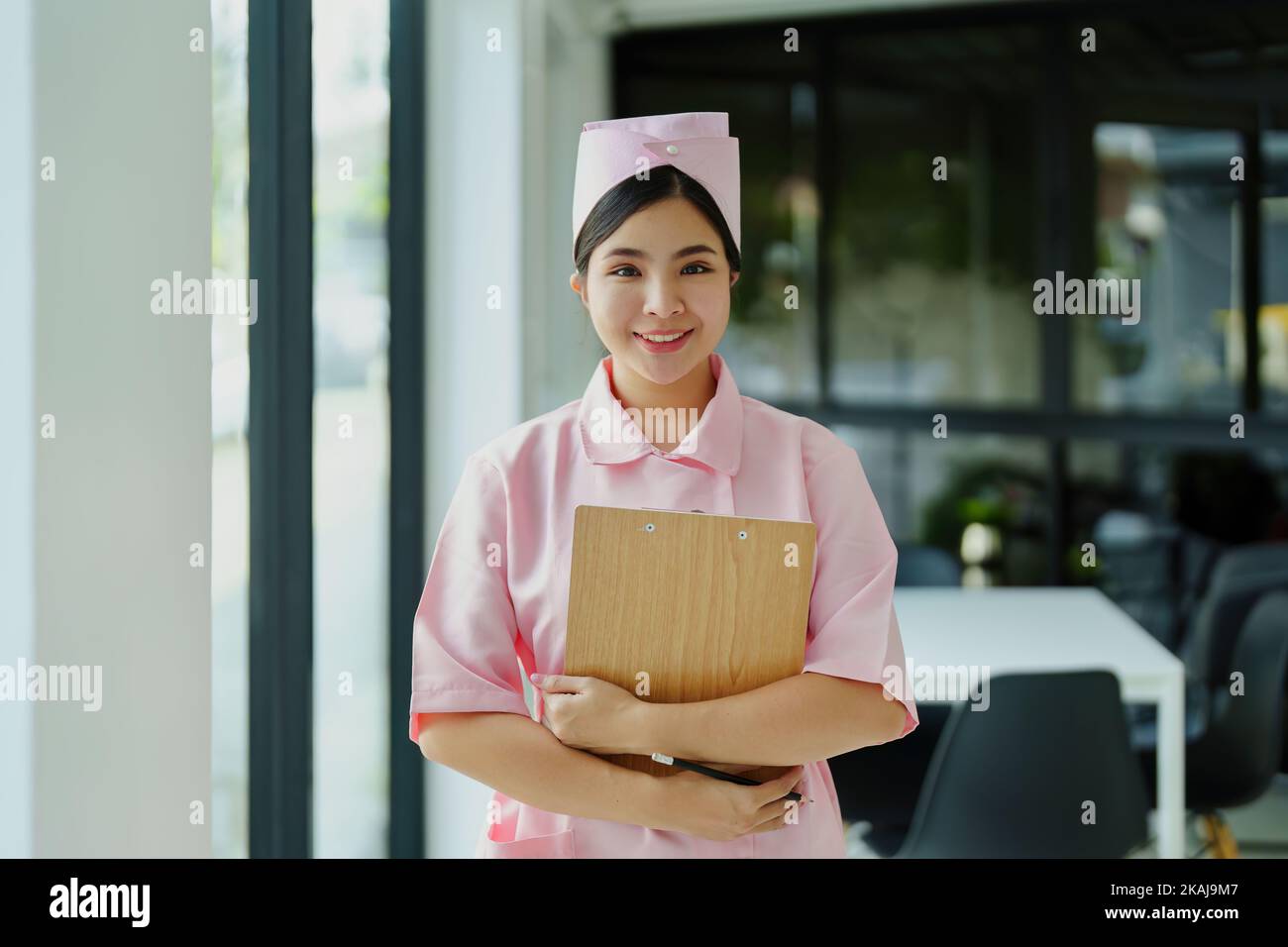 Ritratto di una giovane infermiera in un abito rosa sorridente felicemente Foto Stock