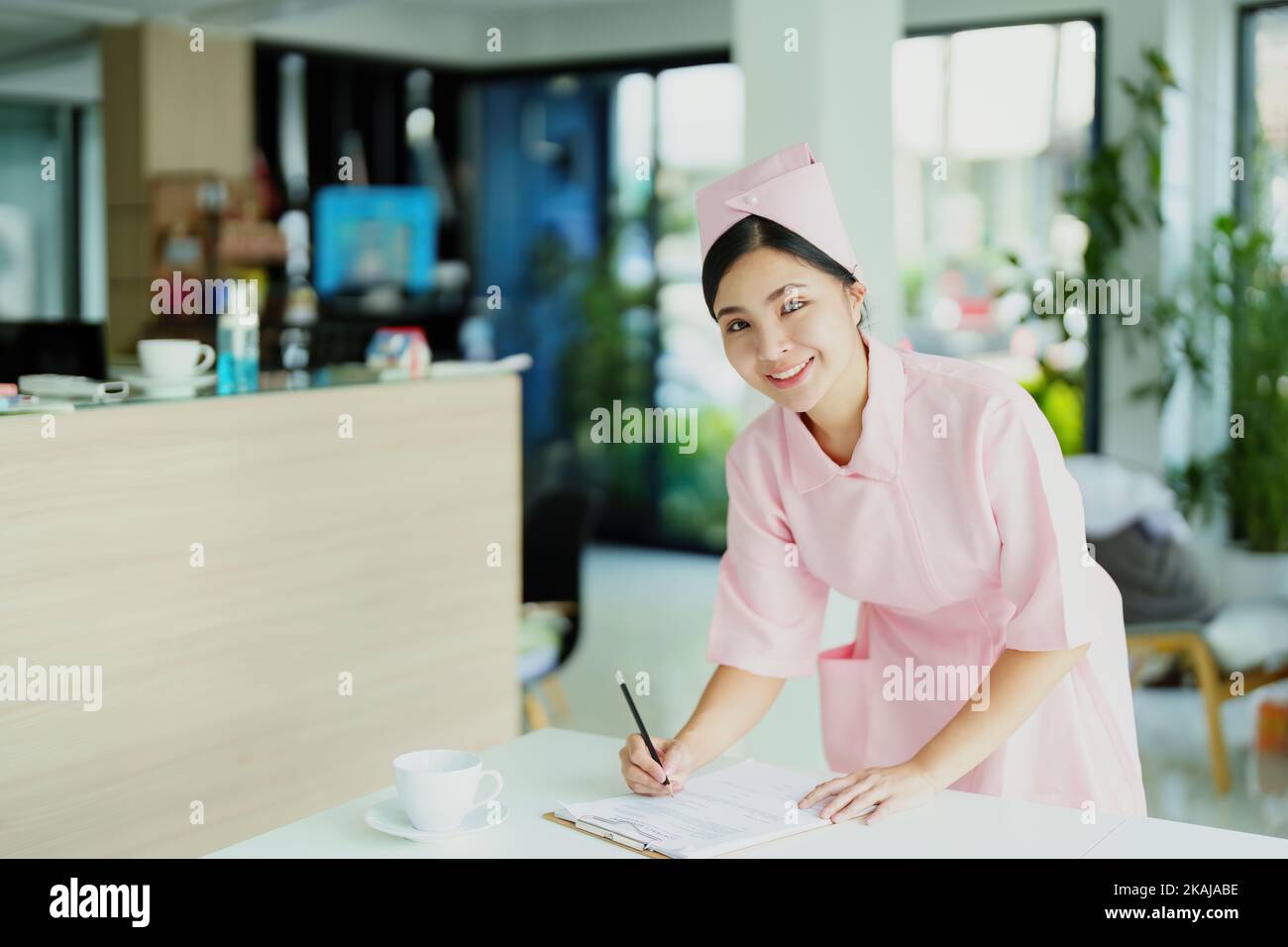 Ritratto di una giovane infermiera asiatica che guarda i documenti del paziente Foto Stock