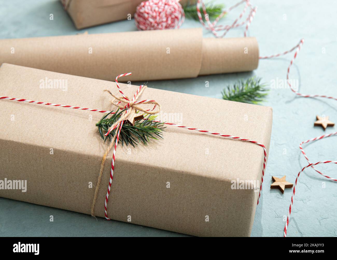 Confezione regalo con carta da imballaggio marrone naturale chiamata carta kraft Sack o carta da sacco. Regali decorati con filo di carta rosso e bianco. Foto Stock