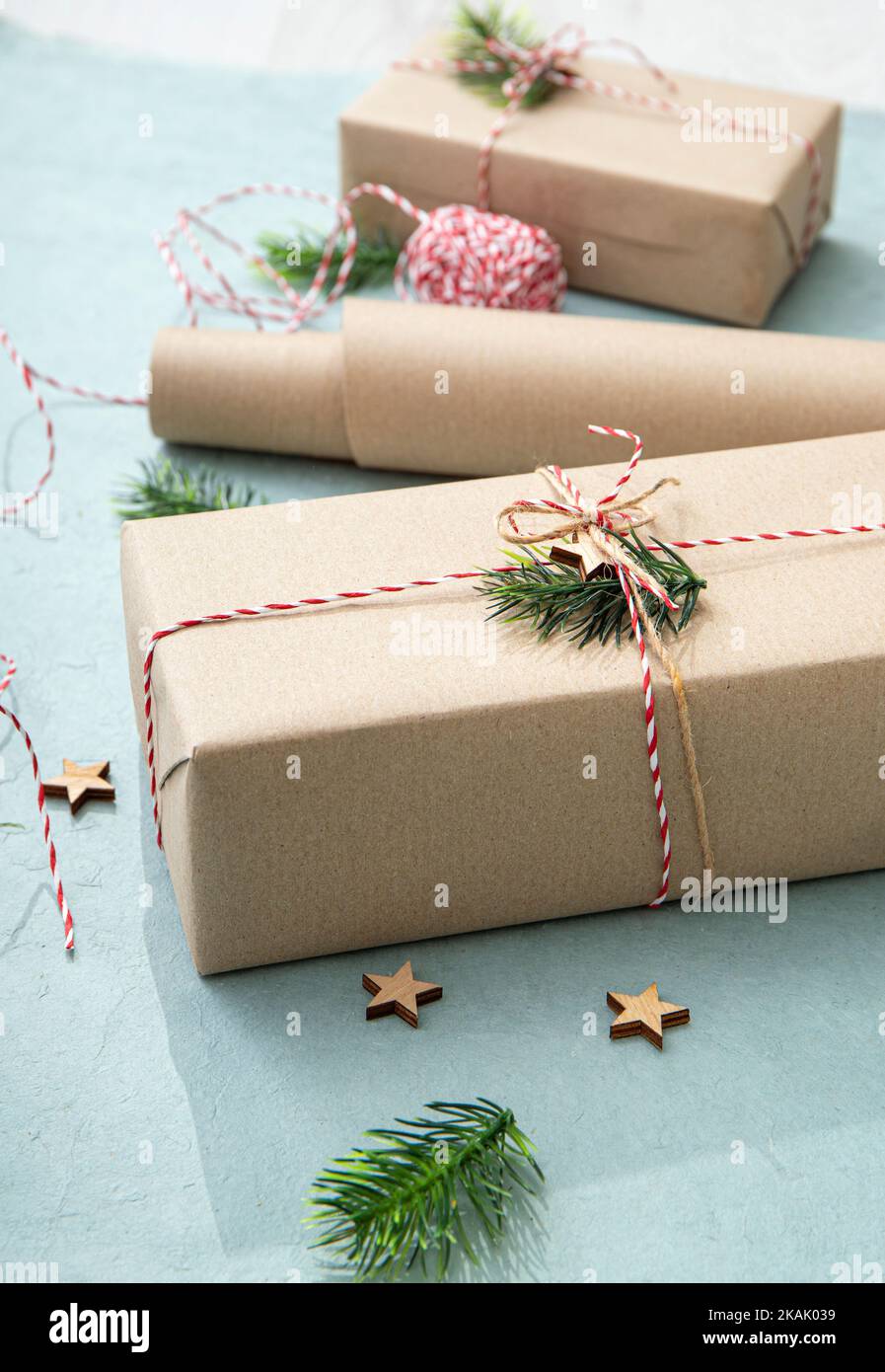 Confezione regalo con carta da imballaggio marrone naturale chiamata carta kraft Sack o carta da sacco. Regali decorati con filo di carta rosso e bianco. Foto Stock