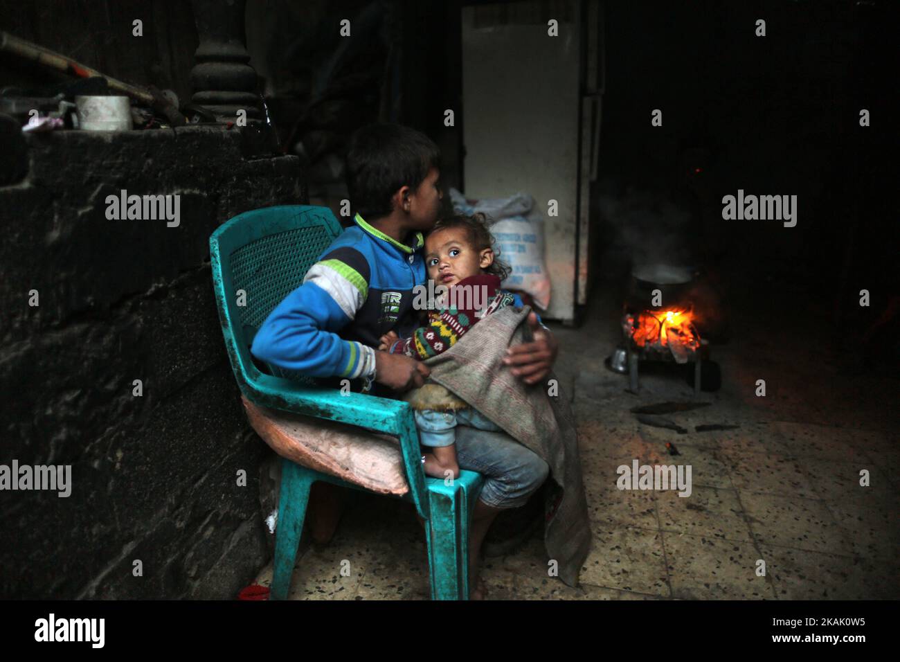 Un ragazzo palestinese gli tiene un fratello minore nelle baraccopoli dei fiori di Sharm, alla periferia del campo profughi di Khan Younis, nella striscia di Gaza meridionale, il 14 dicembre 2016, e l'espansione delle baraccopoli fiori di Sharm, Dove i bambini giocano a piedi nudi nella macchina abbandonata arrugginita e circondata da montagne di spazzatura, è un segno di vita a Gaza, dove la povertà è in aumento e non c'è speranza per il futuro. Mentre Gaza è sempre stata povera, ha peggiorato la situazione di 1,8 milioni di persone che vivono nell'affollata regione costiera dopo l'acquisizione di Hamas nel 2007. (Foto di Majdi Fathi/NurPhoto) *** Please use C Foto Stock