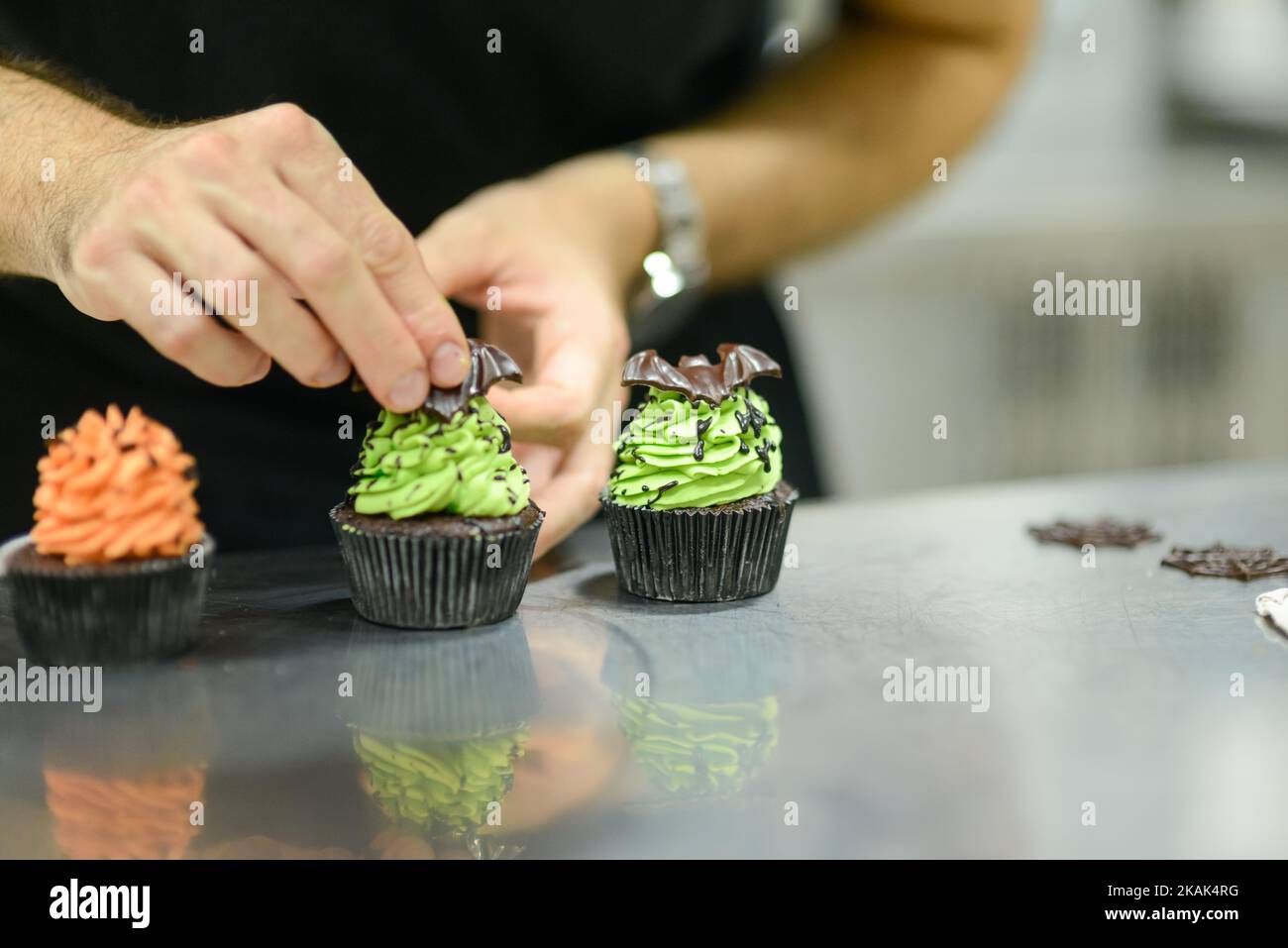 chef artigiano che prepara a mano con glassa e cioccolato ragno vampiro topper Foto Stock