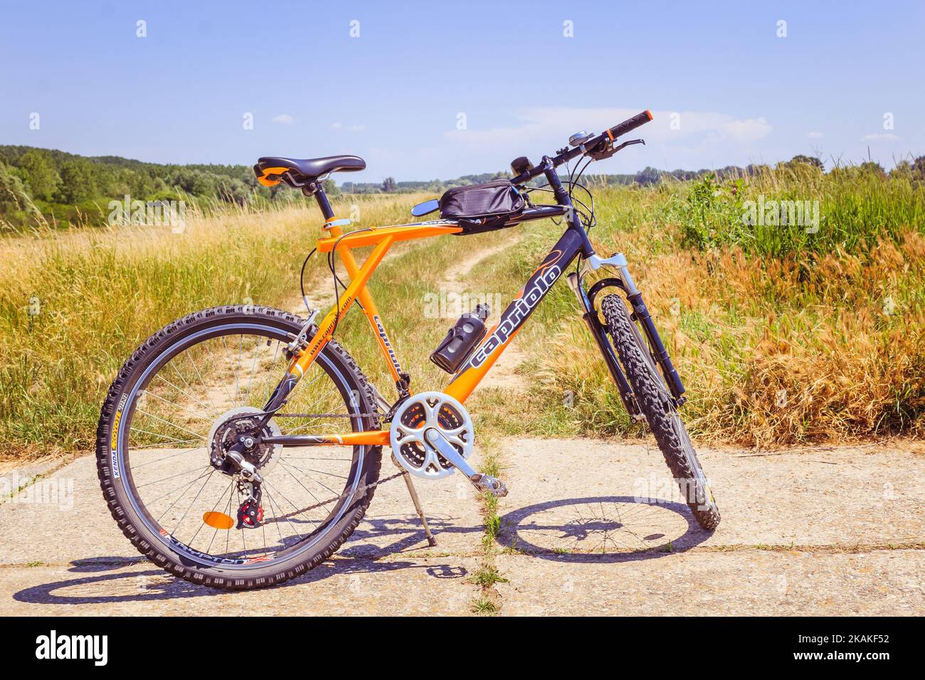 Una bicicletta isolata sul terreno lastricato dal campo verde sotto il cielo blu Foto Stock