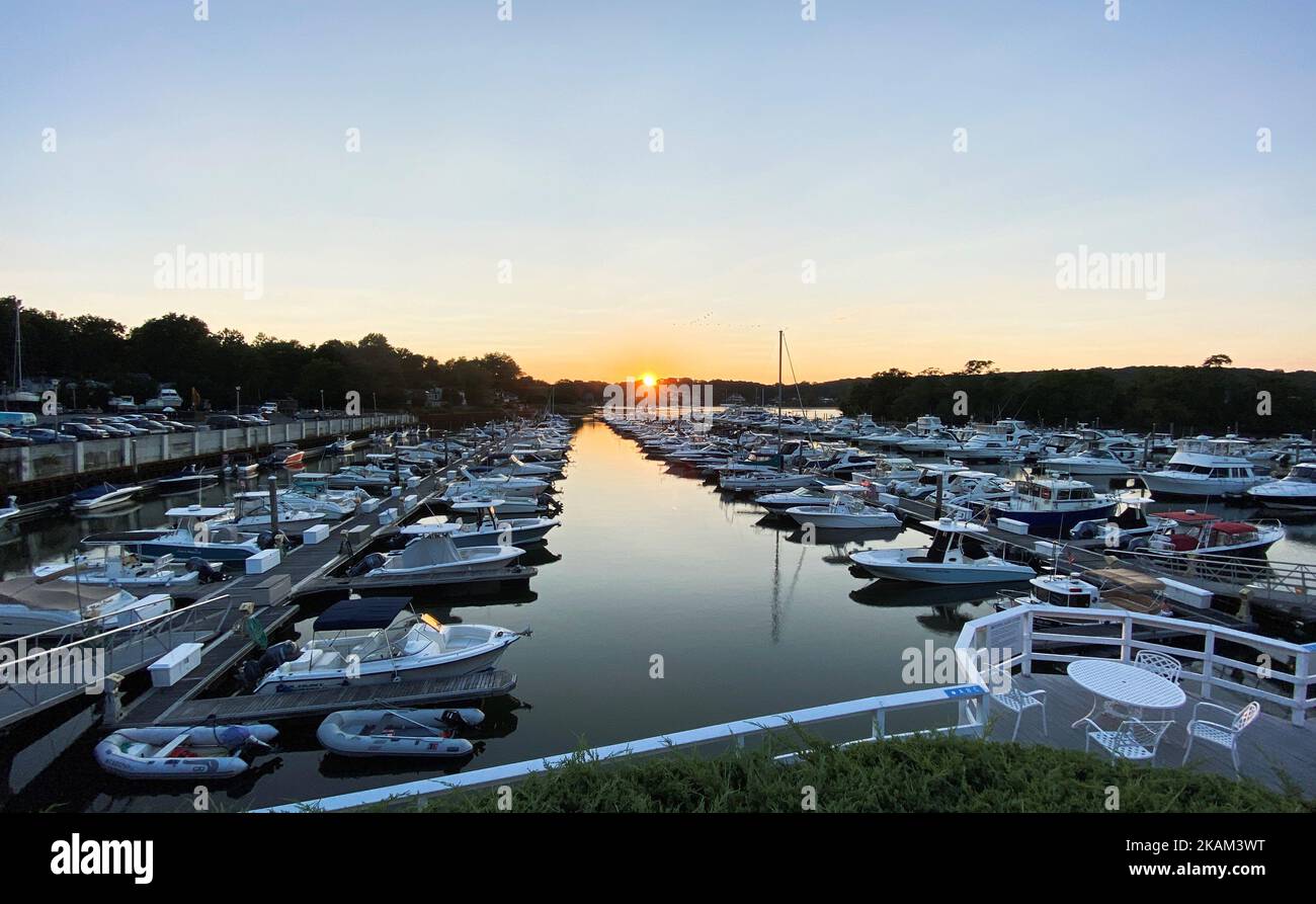 Un porto turistico in una notte estiva piena di barche e il sole quasi fatto tramontare sullo sfondo. Foto Stock