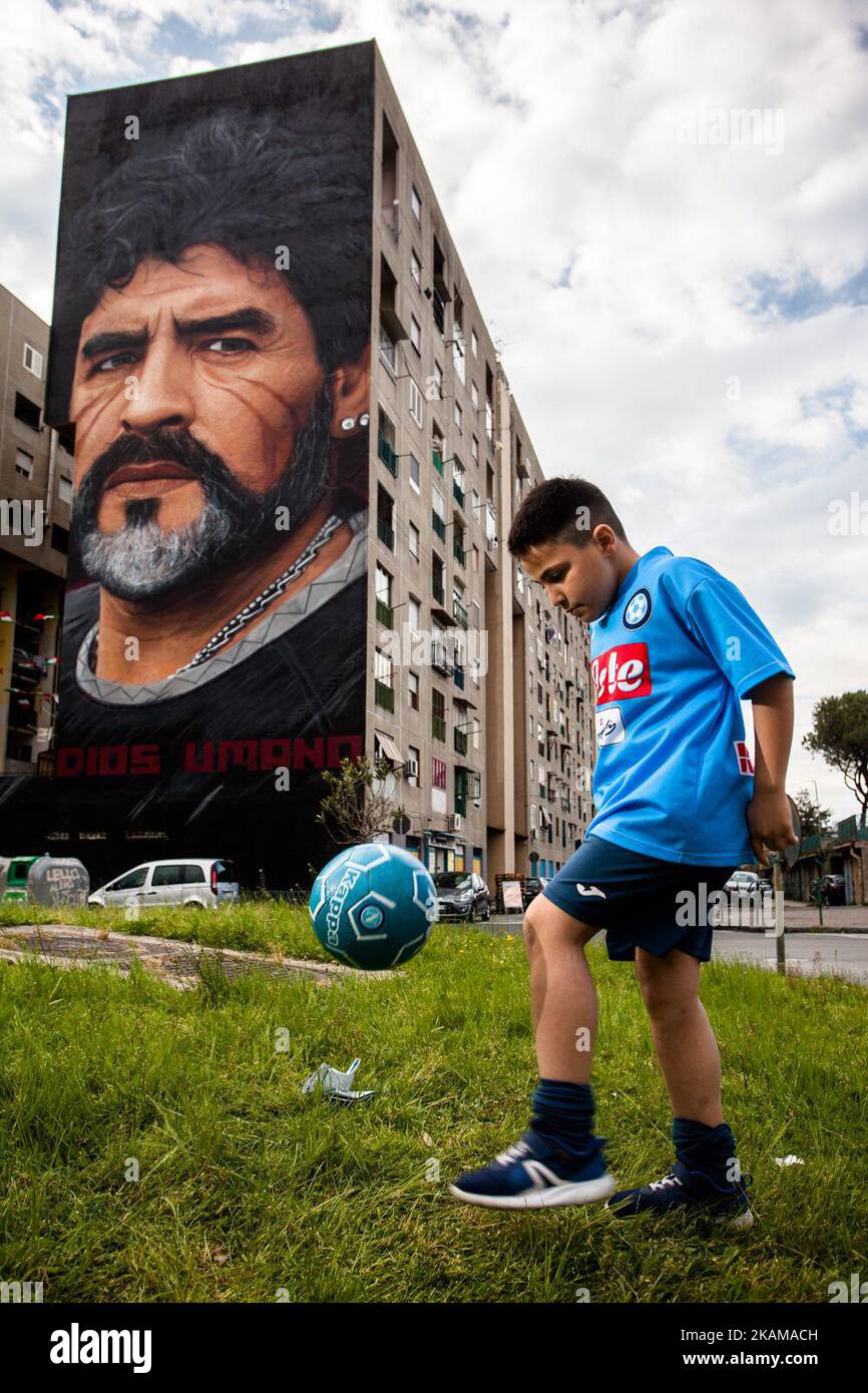 Un bambino che dribbling di Taverna del ferro, San Giovanni a Teduccio, periferica di Napoli EST il 29 marzo 2017 davanti a un Graffiti rivoluzionario di Jorit, dipinto a mano su parete con bombolette spray, Diego Armando Maradona su parete di un edificio. (Foto di Paolo Manzo/NurPhoto) *** Please use Credit from Credit Field *** Foto Stock