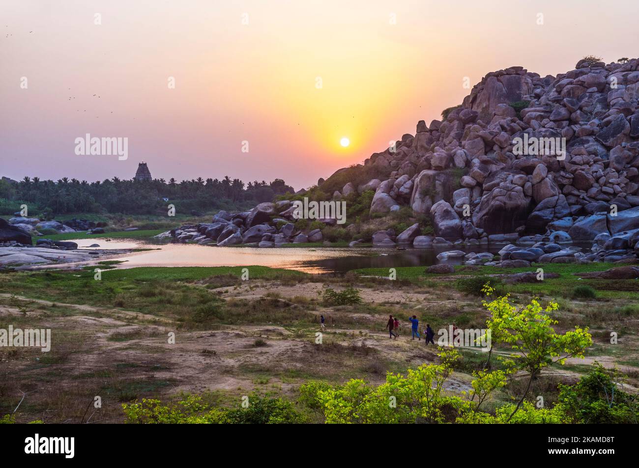 Hampi, Karnataka, India: Un gruppo di escursionisti cammina al tramonto tra enormi rocce di masso sul fiume Tungabadra. Foto Stock